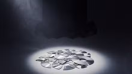 Broken video game discs with an Xbox in the background